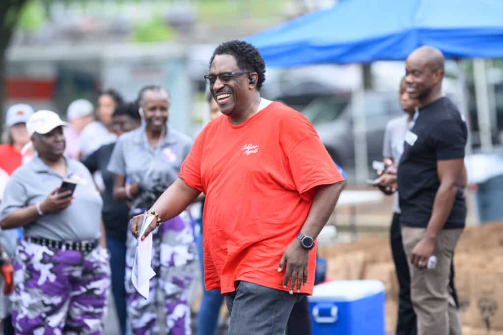 A smiling veteran in a red shirt receiving food assistance at a Soldiers' Angels distribution event