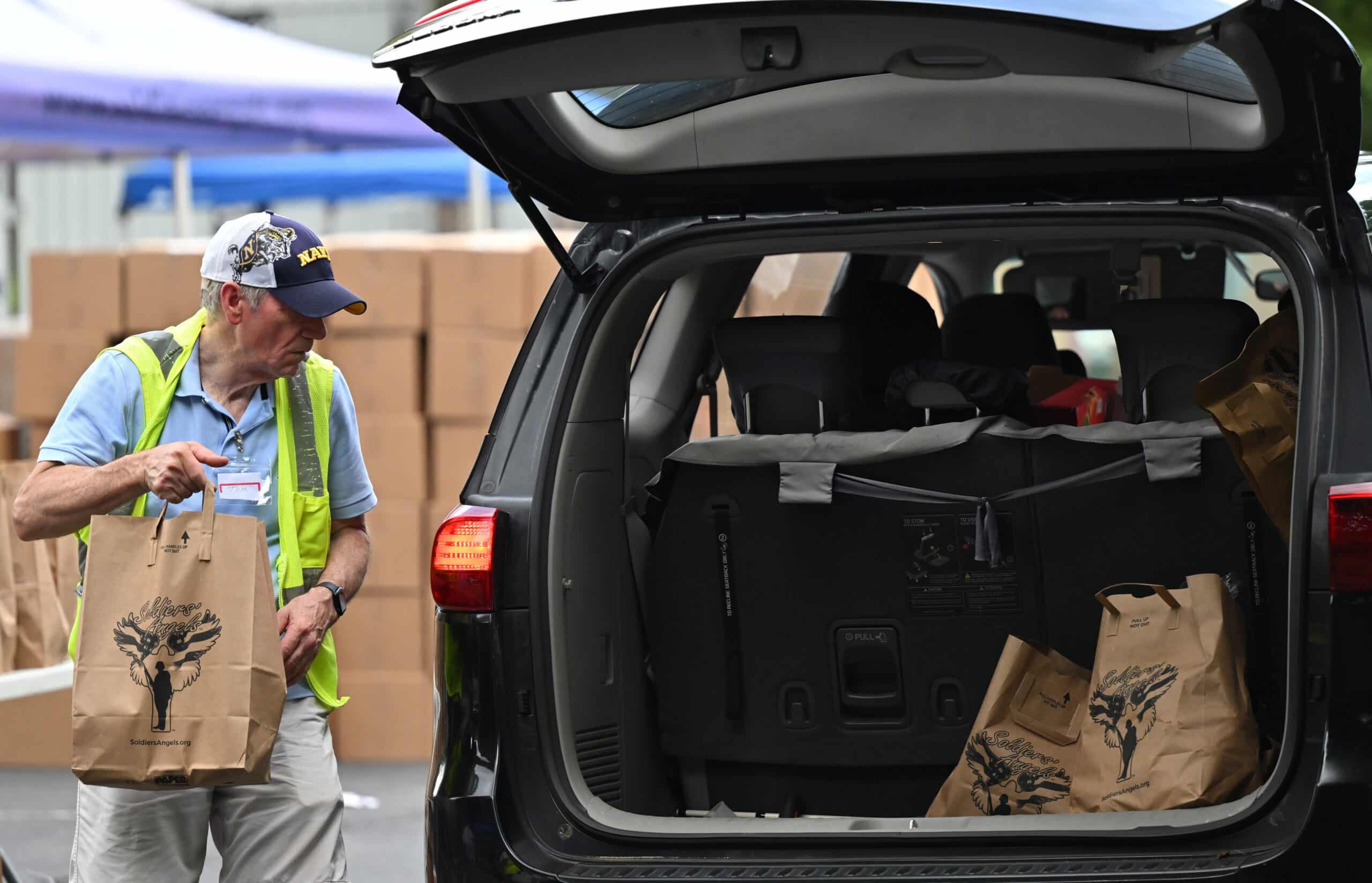 A volunteer transferring bags of groceries into a car at a Soldiers' Angels food assistance event