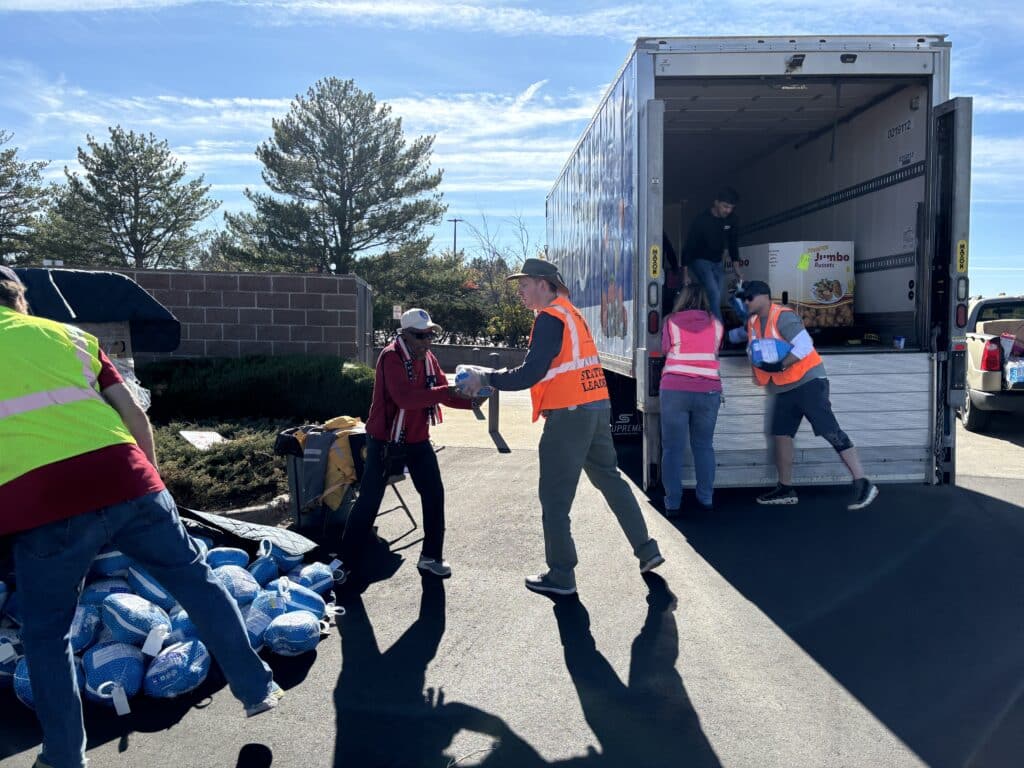 Soldiers' Angels volunteers loading food packages into a large truck at a food event